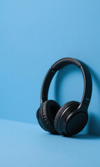 A modern black headset placed on the right side of the frame against a clean blue background, minimalist composition with copy space, studio lighting.