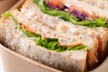 Sandwich tuna mayonnaise with whole wheat bread, lettuce, carrot, tomato and purple cabbage in biodegradable food box