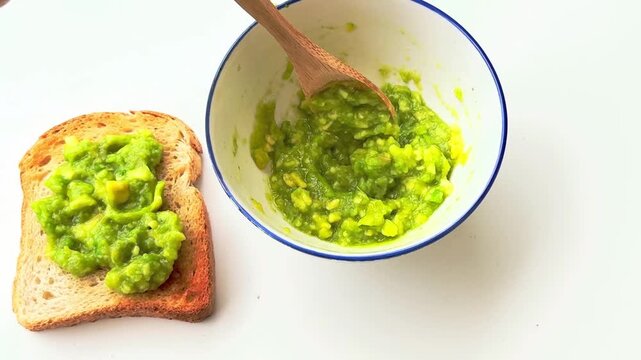 Mixing mashed avocado in a bowl and spreading mashed avocado on toast.