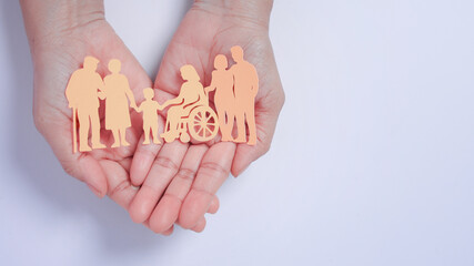 Hands holding inclusive family paper cutout with love illustrating multigenerational care and...