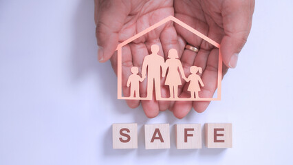 Inclusive family care concept showing secure home protection with safe wooden block text and warm hands holding housing cutout