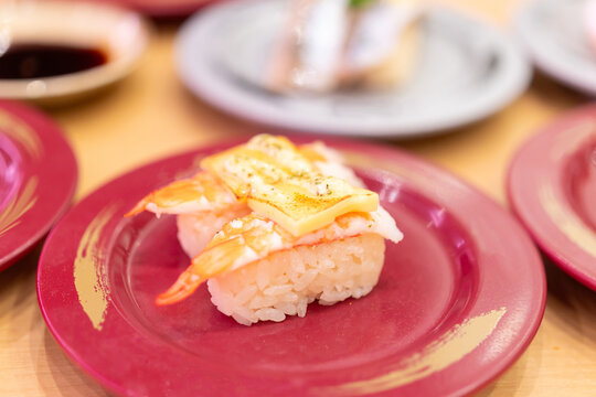 Assorted fresh sushi on colorful plates in a Japanese kaiten sushi restaurant