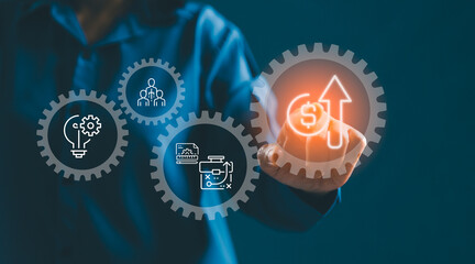 Businessman touching virtual gears and rising revenue icon, representing business strategy, innovation, teamwork and process optimization for profit growth, ROI and digital transformation.
