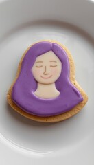 A purple frosted cookie in the shape of a woman's face on a white plate
