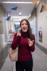 Asian woman laughing talking on mobile phone in mall