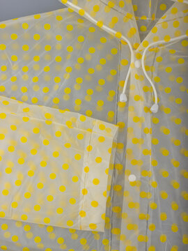 White Ties, Buttons and Sleeve of a Transparent Lemon Yellow Polka-Dot Raincoat, close up