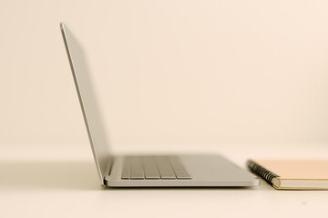 Side view of laptop and notebook on desk with blurred background