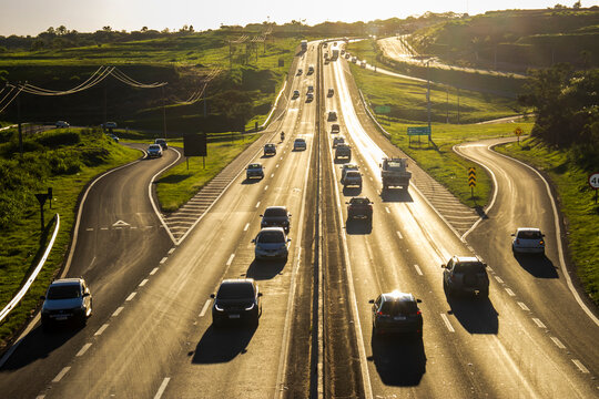 Marilia, SP, Brazil, November 19, 2025. Highway SP-294 in Marilia, at sunset. Intense traffic of cars and trucks flows through the green landscape, illuminated by the golden hour light.