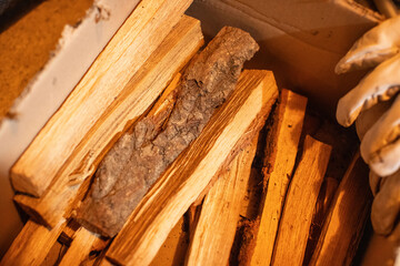 Close-up texture of stacked split dry firewood logs in a box, brown wood grain detail, camping fuel, natural material, warm tone.
