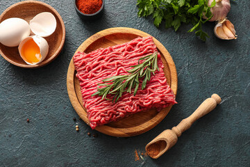 Plate with fresh ground meat, rosemary, eggs, parsley and garlic on green grunge background