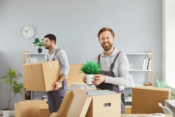 Movers packing boxes for office relocation delivery. One holds a plant as another carries cartons, coordinating transport and logistics. Concept professional team, reliable service, and care.