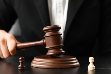 Female mediator with judge's gavel and pawns at table in office, closeup