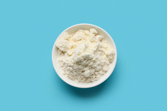 Bowl of powdered milk on blue background