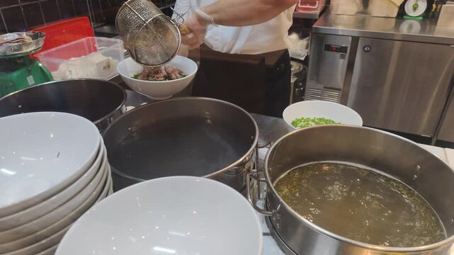 Authentic Pho Cooking requires time. Chef demonstrates Authentic Pho Cooking in restaurant. This Authentic Pho Cooking includes boiling beef in large pot to make traditional tasty broth.