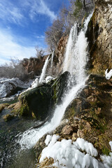 Fototapeta premium Rifle Falls and surrounding ice formations in Rifle Falls State Park near Rifle, Colorado on a bright sunny winter morning.