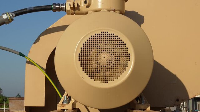 An electrical motor of pumping machine unit is rotate during it operating. Industrial equipment part, close-up and selective focus.