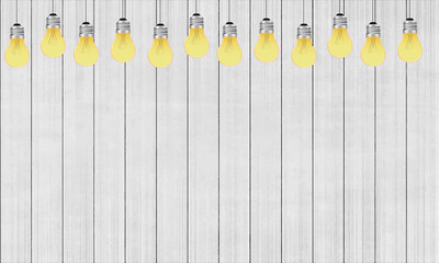 row of glowing yellow light bulbs hanging against white wooden plank background with copy space