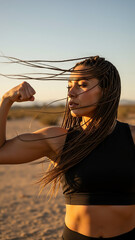 Athletic Indigenous woman flexing biceps in desert at golden hour  