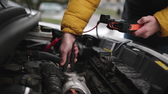 Driver Connects A Jump Starter Battery With Crocodile Clips To Start A Diesel Engine In Cold Temperature