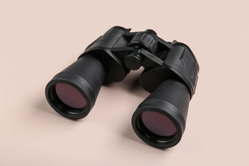 Modern binoculars on beige background