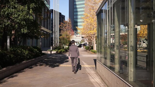 街を歩くビジネスマンの後ろ姿のトラッキングショット