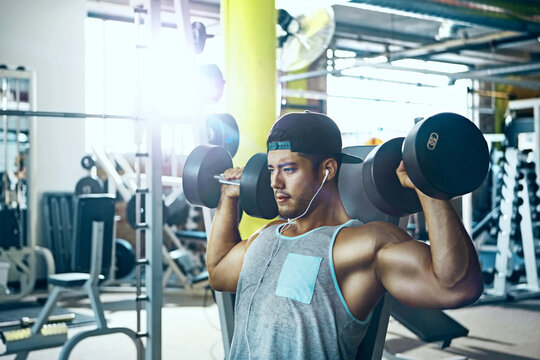 Workout, earphones and man with dumbbells in gym for weightlifting, resistance training and music. Bodybuilder, athlete and weights at health club for competition fitness or bodybuilding with podcast