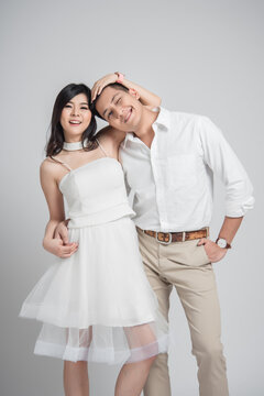 Happy Asian couple wearing white outfits standing together on a clean white background. Romantic portrait showing love, intimacy, and emotional connection, suitable for wedding, Valentine&rsquo;s Day