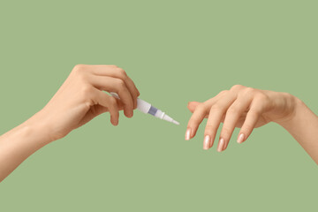 Female hands with cuticle oil pen on green background