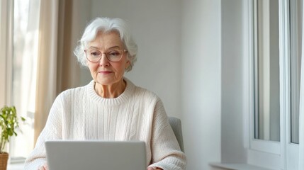 Elderly woman using a laptop at home, representing technology adoption, connection, and learning in senior life.