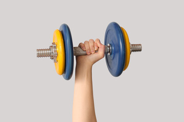 Obraz premium Female hand with dumbbell against grey background, closeup
