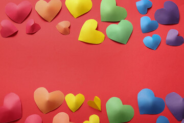 Colorful hearts made of paper on red background. LGBT concept