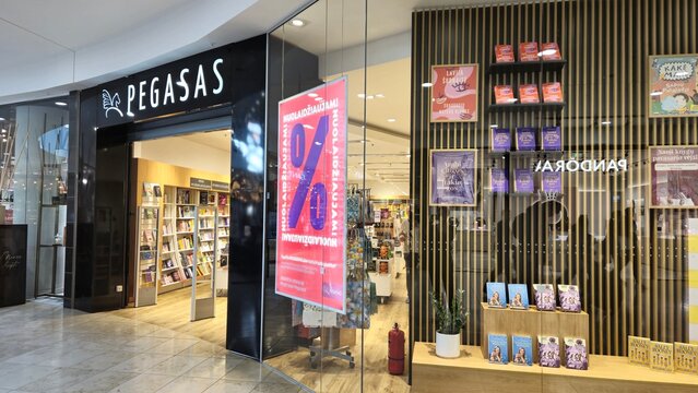 Vilnius Lithuania - 03.29.2025 Pegasas bookstore entrance with red sale poster on glass wall and shelves of colorful books and covers on display, modern store interior and promotional materials 