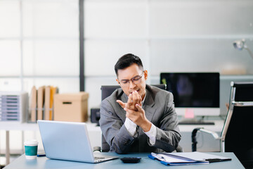 Tired businessman suffering neck pain from office syndrome, feeling muscle strain and discomfort while working long hours at desk with laptop.
