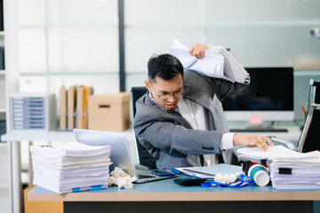 Focused office worker analyzing documents, reviewing business reports with stress and concentration in workplace setting.