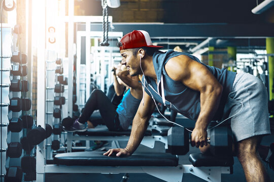Intense, dumbbells and man in gym, training and endurance for body development. Equipment, weight lifting or person in wellness center, energy or fitness for muscle growth, power and core workout