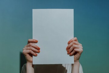 Close up of hands holding a blank white A4 paper horizontally for a flyer or invitation mock up isolated on a light blue to teal gradient background with copy space