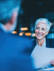 Smiling senior female financial advisor consulting male client, reviewing documents in corporate office for finance planning