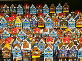 A display of colorful miniature Amsterdam canal houses for sale as souvenirs, each featuring unique shop names like "Cheese Shop" and "Pancakes