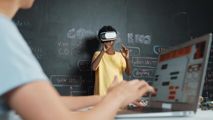 Closeup of school girl hand coding program while african student using VR interact with metaworld. Smart boy wearing virtual reality glasses and playing video games at innovative class. Edification