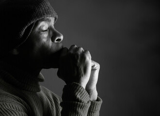 praying to god with hands showing his religious faith with God Caribbean man praying with black background with people stock photo stock image