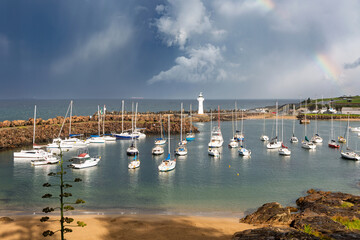 Grey blue storm clouds create a beautifully dramatic sky with a rainbow above the iconic Belmore...