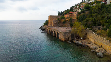 Naklejka premium Alanya, Turkey. Close-up aerial drone view of Alanya Tersanesi shipyard arches and stone structure from sea perspective in summer.. Aerial View
