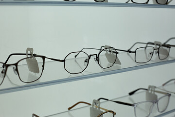 Shelf with glasses of different formats. Eyeglass store shelf with wide variety of temple and frame designs. Buying new glasses after vision loss. Glasses for vision on glass shelf