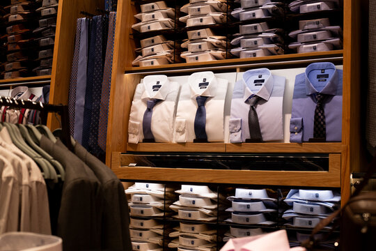 Interior of classic business clothing store featuring shirts and jackets. Examples of perfect shirt and tie combination on display in premium store. Shopping and purchasing luxury clothing