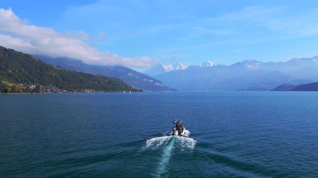 Powerboat Swiss Alps Grindelwald Jungfrau mountains Bernese Oberland Thunersee Lake Thun aerial drone Thun Switzerland Schweiz Fall Autumn sunny morning low clouds haze Interlaken follow forwards