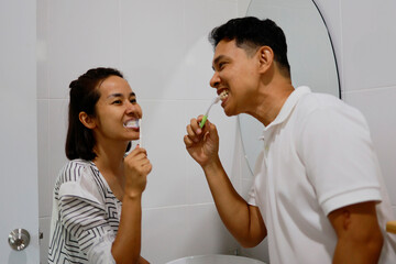 Woman and man brushing her teeth in the morning.