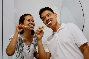 Woman and man brushing her teeth in the morning.