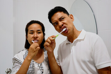 Woman and man brushing her teeth in the morning.