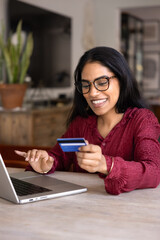 Happy satisfied Indian bank customer woman paying for online purchase by credit card from home,...