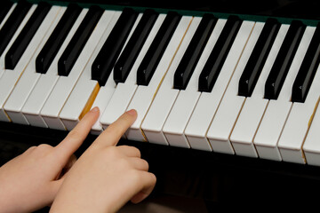 Children's hands pressing white and black keys on a piano, learning to play music, symbolizing musical education and practice